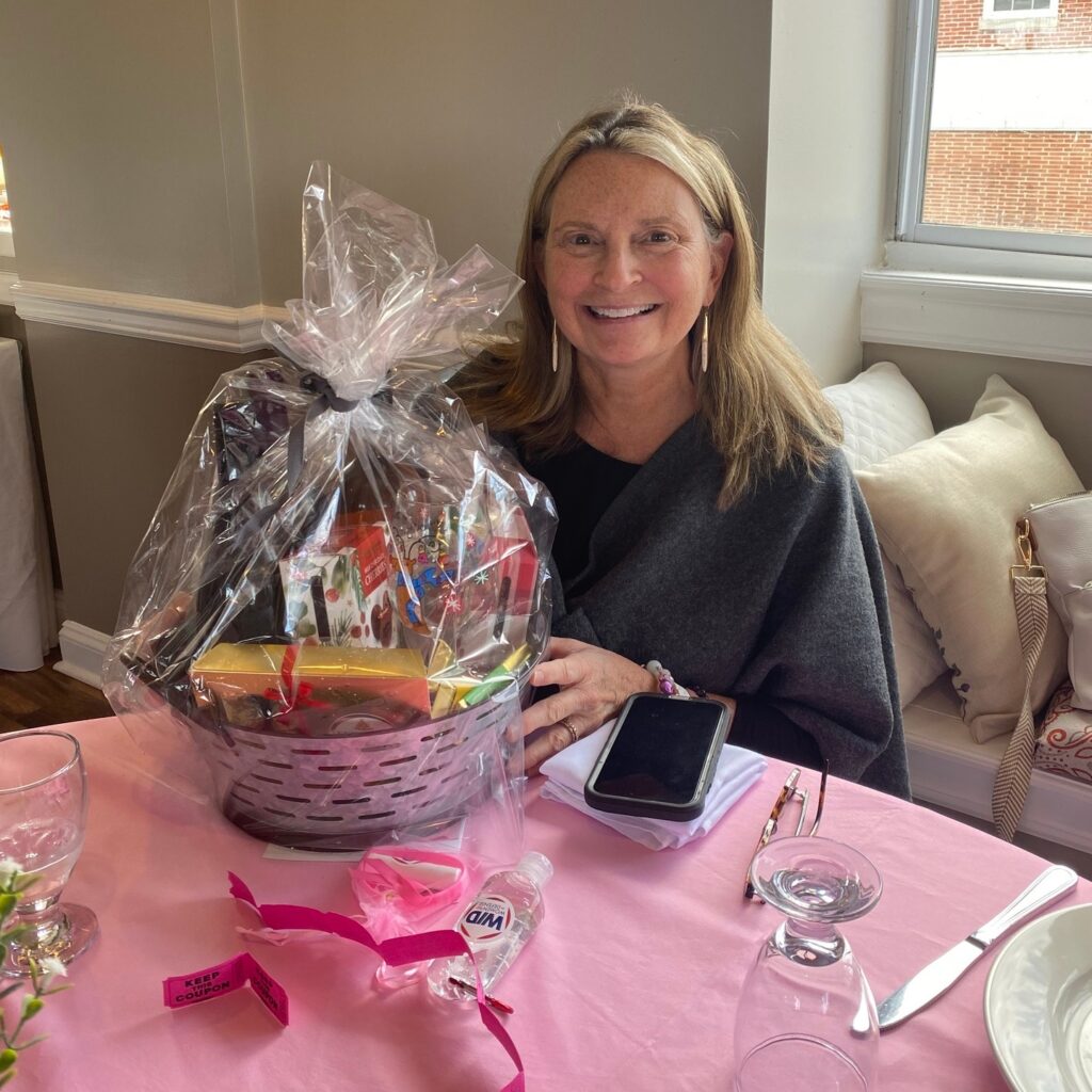 A member of WID Mid-Atlantic poses with a prize at the 2024 Annual Breast Cancer Awareness Lunch.